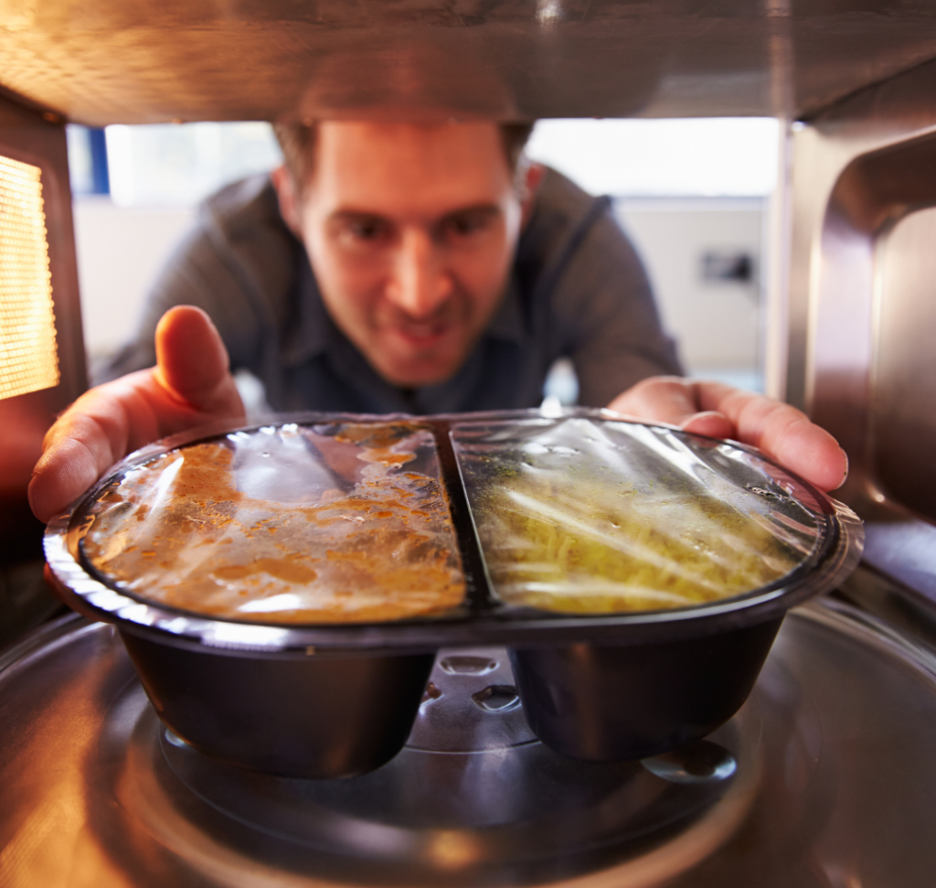 En la imagen se muestra un hombre metiendo comida a un microondas